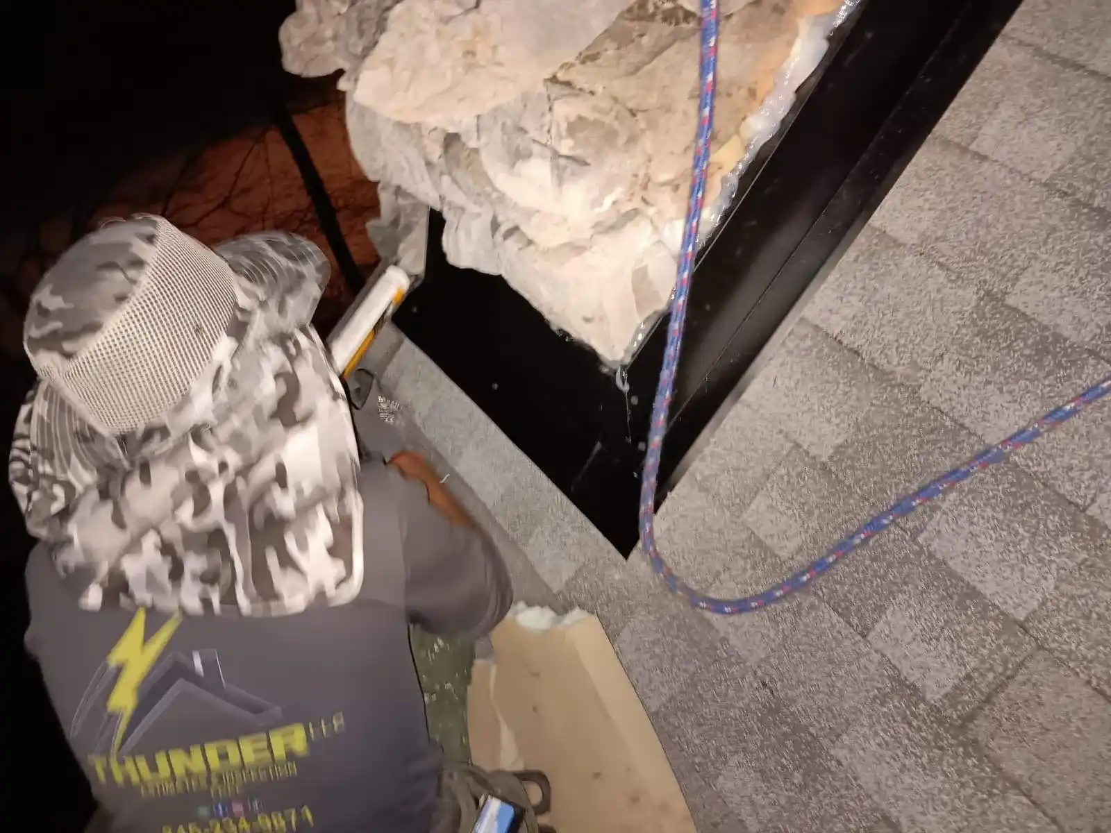 Roofer sealing step and counter flashing on stone chimney base