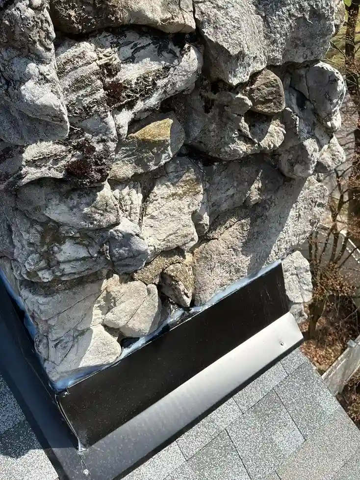 Stone chimney base with metal flashing