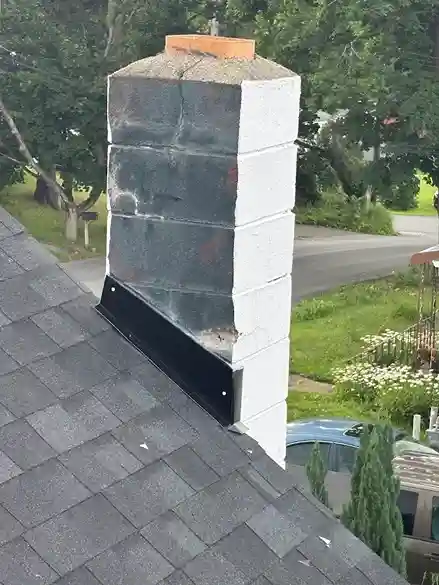 White block chimney on roof with newly installed black flashing