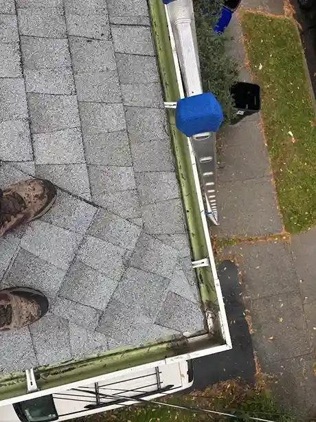 Roofer installing protective mesh gutter leaf guard system