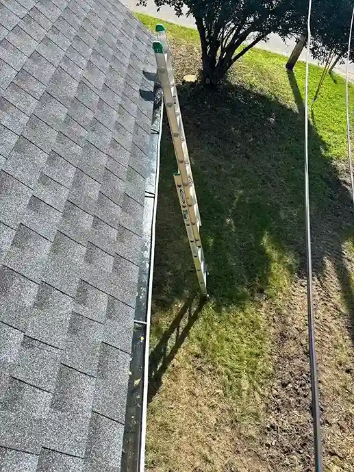 Worker clearing clogged downspout during seasonal maintenance