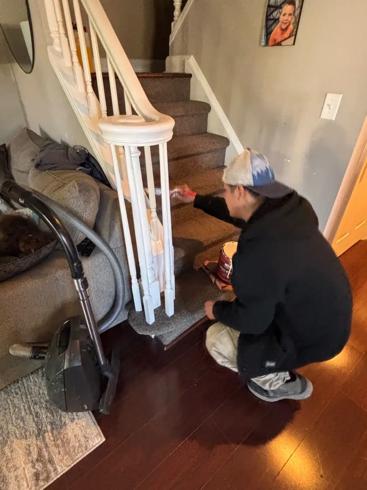 Painter painting stair balusters white with precise brushstrokes