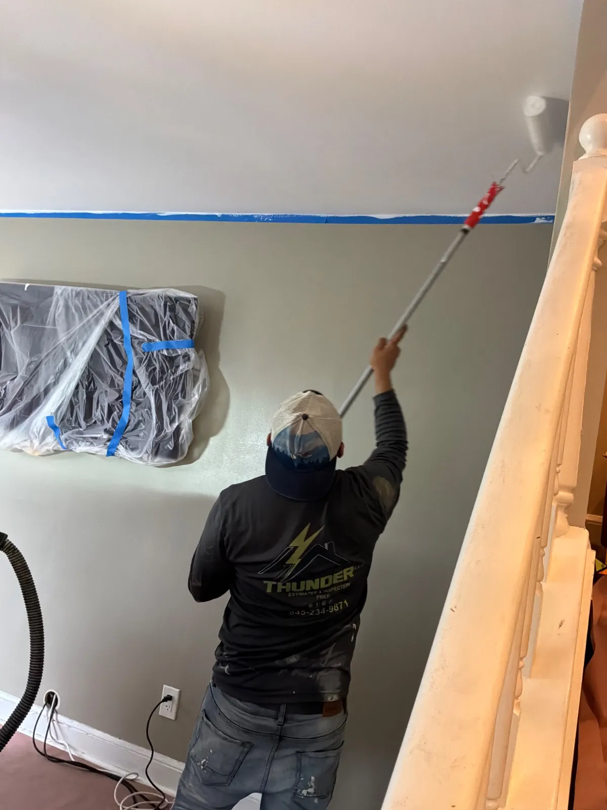 Professional painter rolling white paint on high ceilings