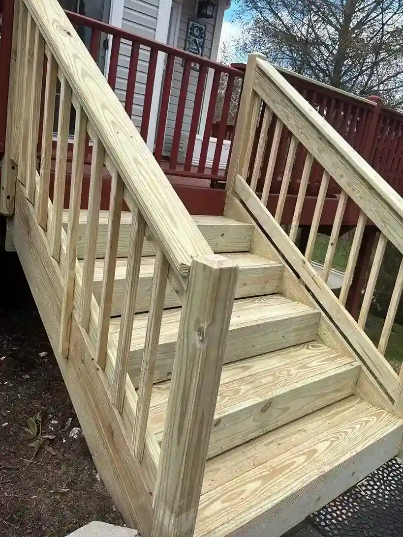 Newly built natural wood staircase leading to a red deck