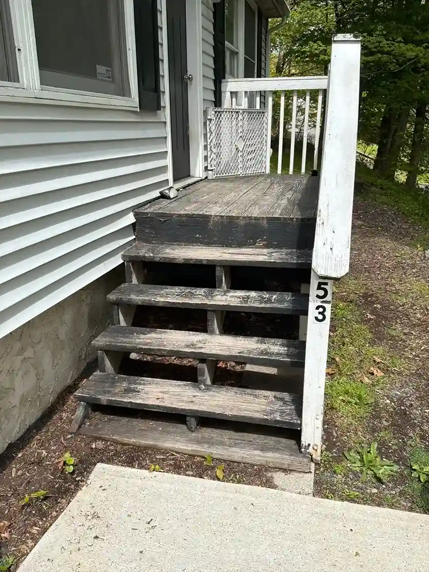 Weathered grey wooden porch stairs with peeling old paint