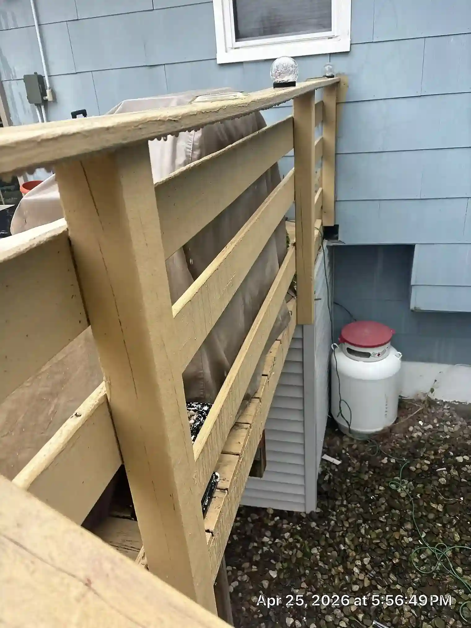 Detail of weathered yellow wood deck railing against house wall