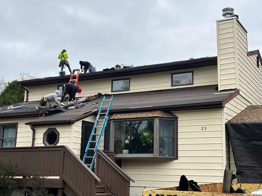 Roofing crew stripping shingles and prepping deck on a house