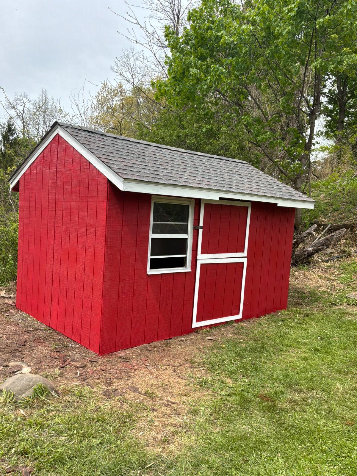 Red backyard shed with a new gray architectural shingle roof and white trim