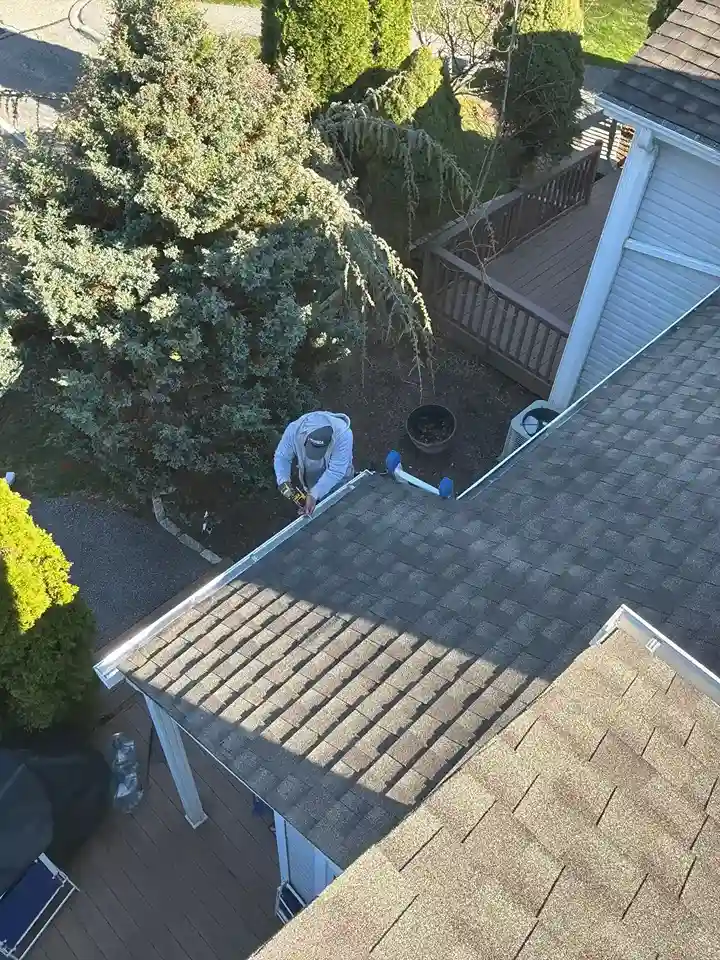 Roofer on ladder installing aluminum drip edge flashing
