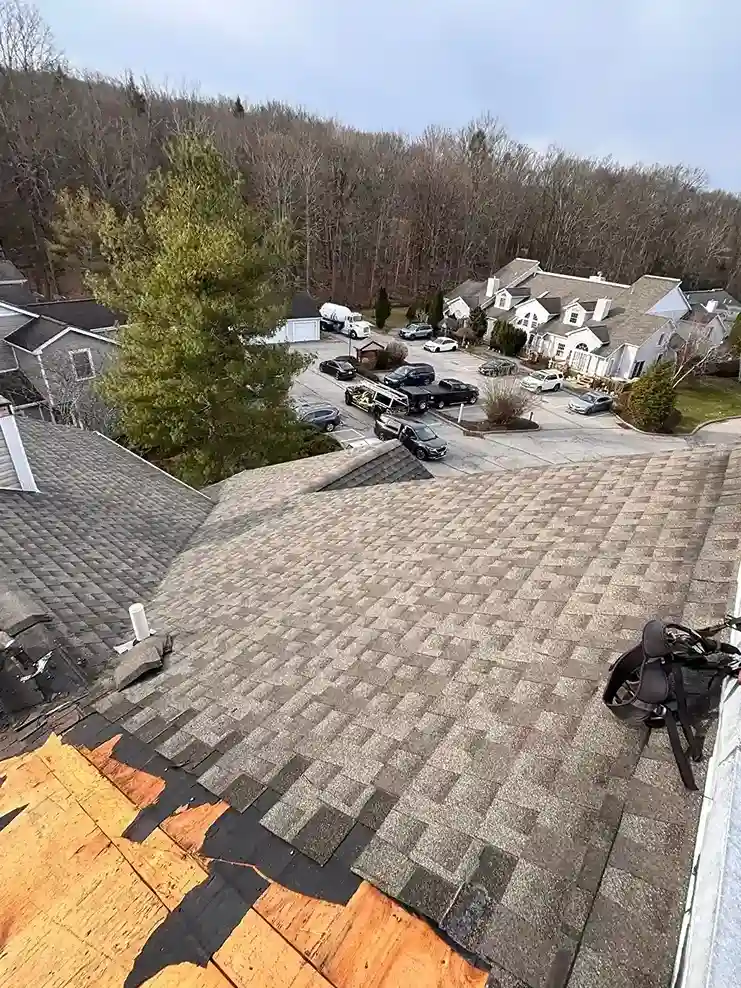 Wide view of finished dark shingles roof with active work section