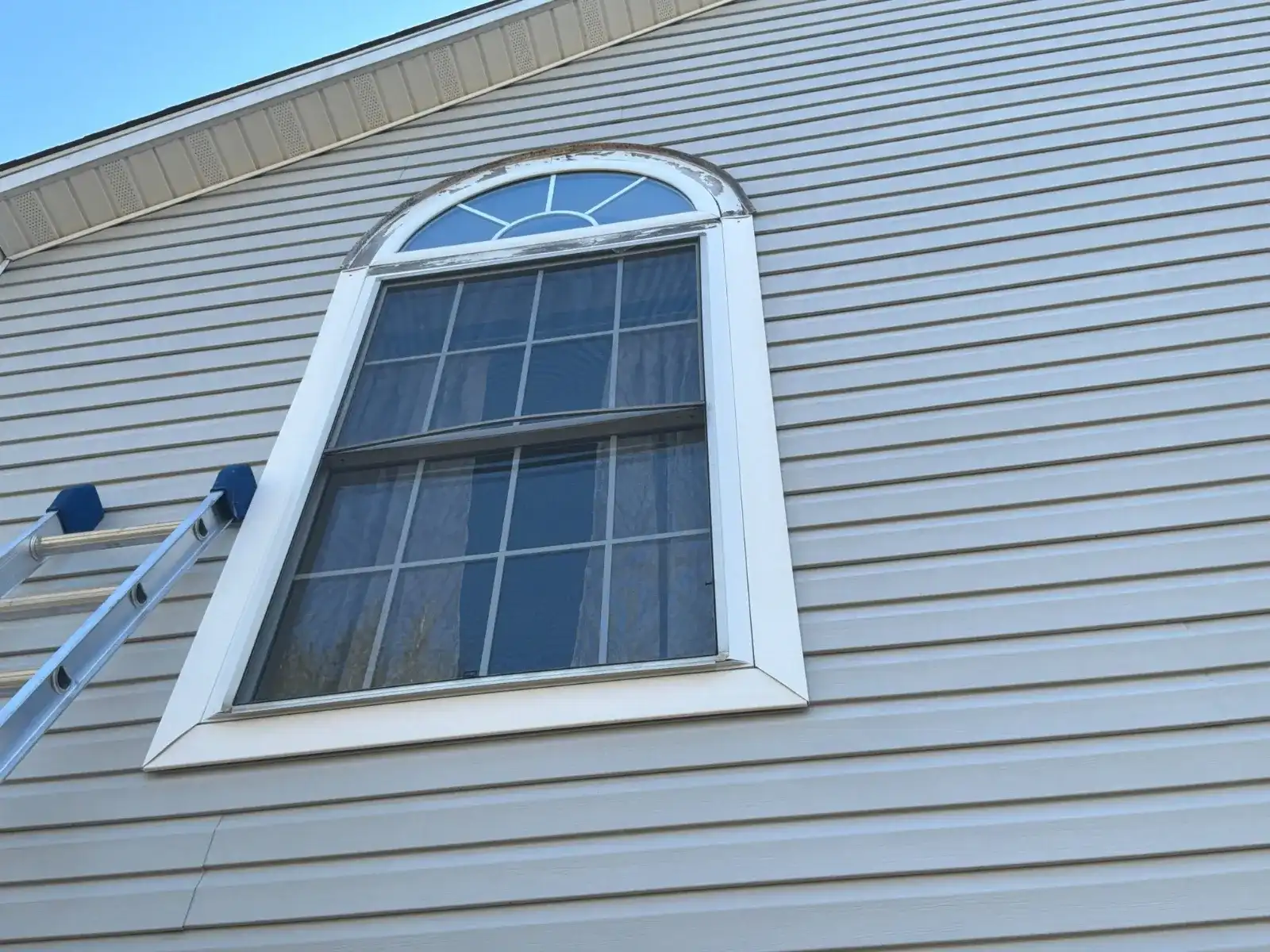 Grey vinyl siding installed around an arched window