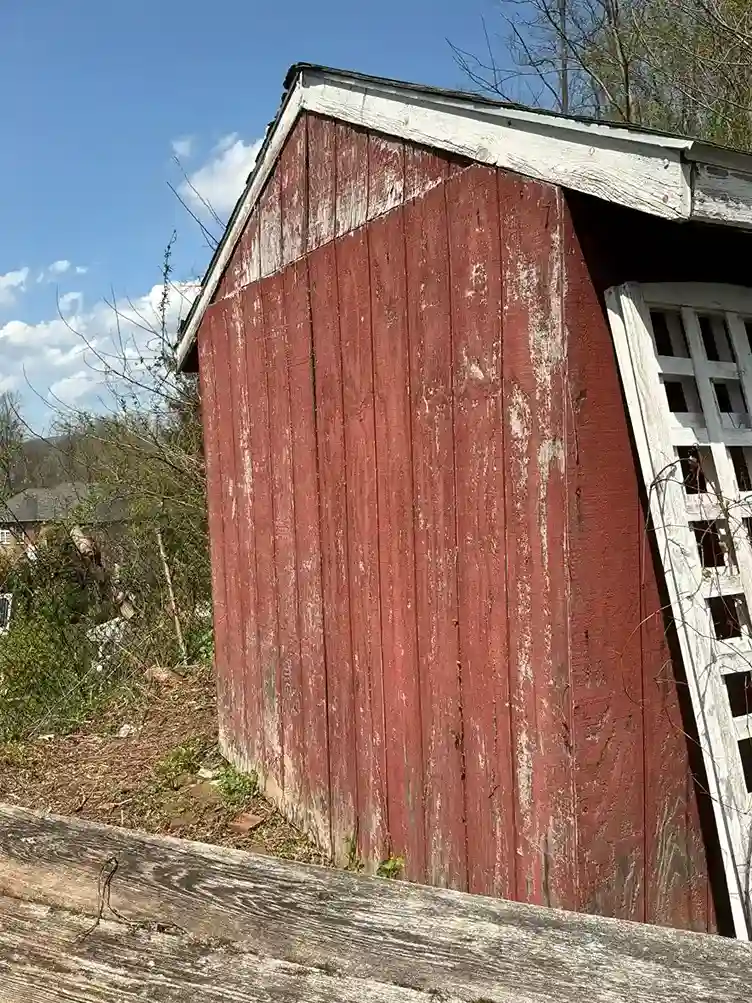 Sun faded peeling red paint on old vertical wood siding